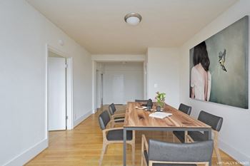 a room with a wooden table and chairs and a large painting on the wall
